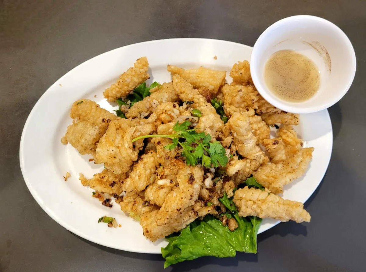 Plate of fried calamari with cilantro and dipping sauce
